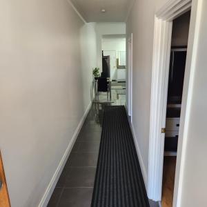 a hallway with white walls and a black tile floor at City Villa 39 Blende st Broken Hill NSW 2880 in Broken Hill