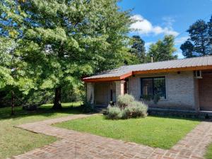 a small brick house with a tree and a pathway at La Juana Quinta in General Rodríguez