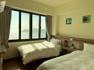 東引鄉的住宿－東引海悅樓民宿，酒店客房设有两张床和大窗户。
