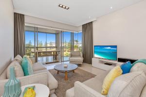 a living room with couches and a flat screen tv at Wave Culture 1204 Beach Bliss - Apartment with complex Pool & Spa in Kingscliff