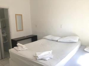a white bed with two towels on top of it at Casa Brisa in Fortaleza