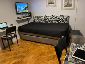 Habitación con cama, escritorio y TV. en Ruffus's Apple Baires en Buenos Aires