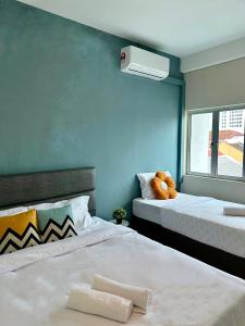 um quarto com 2 camas e um urso de peluche sentado em cima em Swing & Pillows @ Malabar em George Town