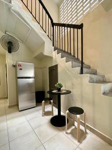 uma cozinha com uma mesa, um frigorífico e escadas em Swing & Pillows @ Malabar em George Town
