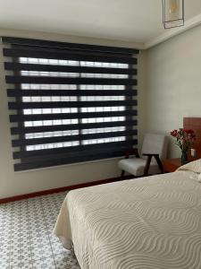 um quarto com uma janela com uma cama e uma cadeira em Casa Sol em Oaxaca de Juárez