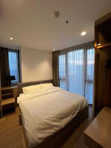 een slaapkamer met een groot wit bed en ramen bij Condo Edge Central in Pattaya