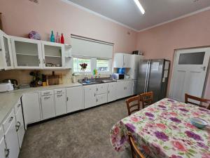 a kitchen with white cabinets and a table and a refrigerator at Spacious Holiday Home-Ramco in Waikerie