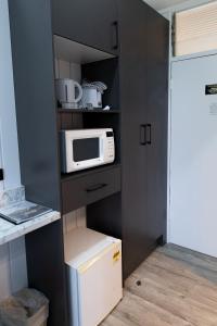 a small kitchen with a microwave and a refrigerator at Garden Motor Inn Gundagai in Gundagai