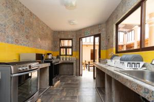 cocina con encimeras y paredes amarillas y grises en Tierra Alta Hostal en San Cristóbal de Las Casas