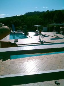 uma piscina com mesas e guarda-sóis num pátio em Pousada Sitio Bom Fim em Serra Negra