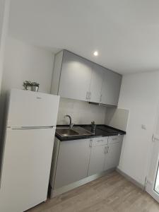 a white kitchen with a sink and a refrigerator at The Islands in Faro