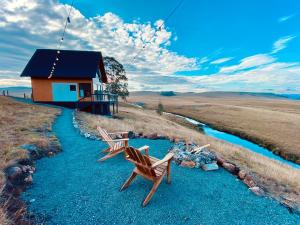 two chairs sitting on a stream in front of a house at Cabanas Arroio Da Serra in Cambara do Sul