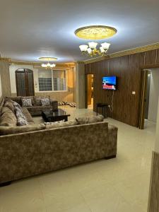 uma sala de estar com um sofá grande e uma televisão em شقه مفروشه بمدخل مستقل و موقف لثلاث سيارات مع ساحات خارجيه em Irbid