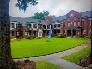 a large brick building with a flag in the grass at 2br Hideaway just 2 miles from Beale St and Overton Square! in Memphis