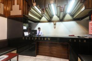 a man standing at a reception desk in a restaurant at Super Collection O Hotel President in Guwahati