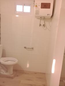 a white bathroom with a toilet and a window at Tákate DoS in La Paloma