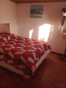 a bedroom with a bed with a red and black quilt at Tákate DoS in La Paloma