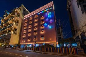 un hotel con una señal encendida en el costado. en Jangyu Almond Kids Hotel, en Gimhae