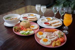 a wooden table with plates of breakfast food and drinks at Gate43 Garden Villa in Bangkok
