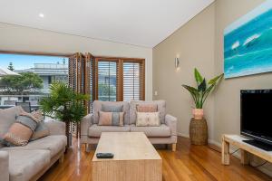 a living room with two couches and a tv at Byron Bay Accom Unit 1 2 Fletcher Street Pipis on the Beach 1 in Byron Bay