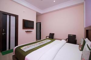 een slaapkamer met een bed en een tv aan de muur bij OYO Hotel Chandni in Dharmsala
