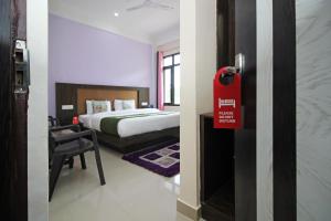 una camera con un letto e una porta con un cartello rosso di OYO Hotel Chandni a Dharamsala