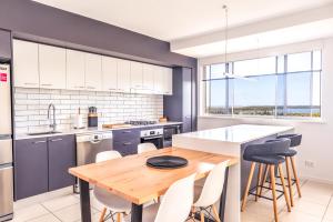 a kitchen with a wooden table and white cabinets at Grandview Apartments in Ballina