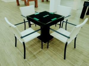 une table noire avec deux chaises blanches et un plateau en verre dans l'établissement Flat Encantador na Praia dos Carneiros, à Tamandaré