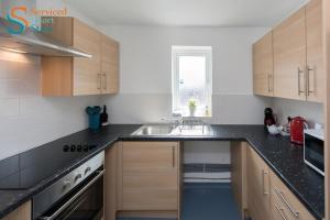 a kitchen with wooden cabinets and a sink at Stylish ground floor apartment in Margate