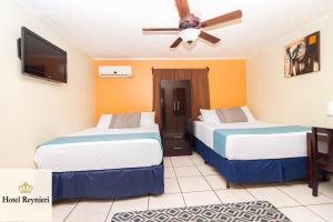 two beds in a hotel room with a ceiling fan at Hotel Reynieri in Comayagüela