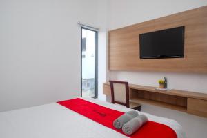 a bedroom with a bed and a television on a wall at RedDoorz near Sleman City Hall Yogyakarta in Yogyakarta