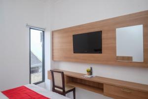 a bedroom with a television on a wall with a desk at RedDoorz near Sleman City Hall Yogyakarta in Yogyakarta