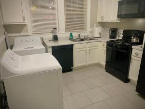 a kitchen with white cabinets and black appliances at 2br Hideaway just 2 miles from Beale St and Overton Square! in Memphis