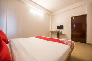 Schlafzimmer mit einem Bett mit einer roten und weißen Decke in der Unterkunft OYO Primrose Regency Near Amanora Mall in Kharadi