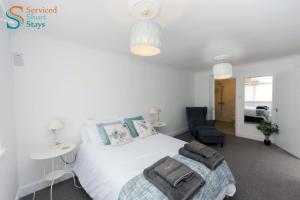 a bedroom with a white bed and a chair at Stylish ground floor apartment in Margate