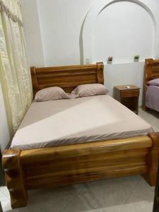 ein Holzbett mit weißer Bettwäsche und Kissen in der Unterkunft Para buenos gustos, buen confort in Tumba