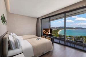 a bedroom with a bed and a view of the ocean at Ascott Dadonghai Bay Sanya in Sanya