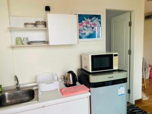 a kitchen with a microwave and a refrigerator at 1 Double bedroom Swimming pool Apartment for Rent in UdonThani With Gym Laundry in Udon Thani
