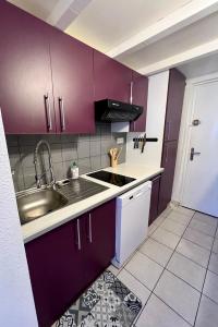 a kitchen with purple cabinets and a sink at Le Pitay’Appartement in Saint-Gilles les Bains