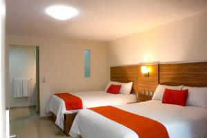 a hotel room with two beds with red pillows at La Casa del Reloj - Zona de Hospitales in Mexico City