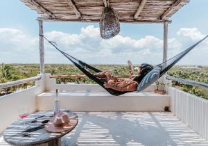 LunArena Boutique Beach Hotel Yucatan Mexico في إل كويو: امرأة مستلقية على أرجوحة على شرفة