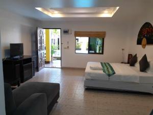 a bedroom with a bed and a couch and a tv at Phratamnak Inn - 100 meter from Beach in Pattaya South
