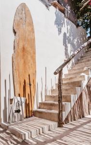 un conjunto de escaleras con una tabla de surf apoyada en una pared en LunArena Boutique Beach Hotel Yucatan Mexico en El Cuyo