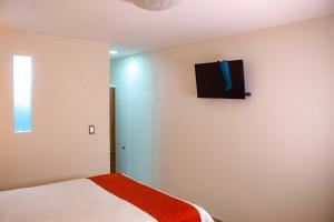 a bedroom with a bed and a tv on the wall at La Casa del Reloj - Zona de Hospitales in Mexico City