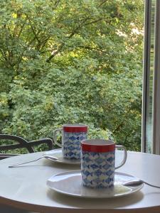 due tazze sedute su un tavolo di fronte a una finestra di King size lounge 76m2 de confort au centre ville a Mulhouse