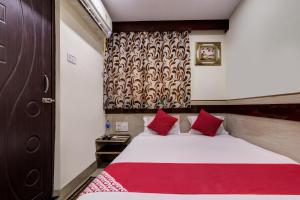 a bedroom with a large bed with red pillows at OYO Hotel Satguru in Jamshedpur