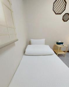 ein weißes Bett in einem weißen Zimmer mit einem Tisch in der Unterkunft Blau Guesthouse in Gyeongju
