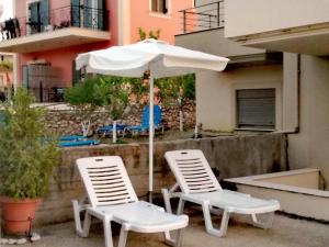 - 2 chaises blanches et un parasol sur la terrasse dans l'établissement VISTA DI MARE, à Lixouri