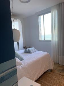 a white bedroom with a bed and a window at Apartamento Renovado na beira da Praia in Vila Velha