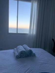 a bedroom with a bed with towels on it with a window at Apartamento Renovado na beira da Praia in Vila Velha